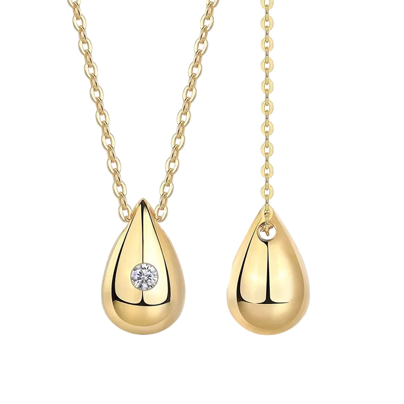 Gold teardrop pendants with a diamond on a white background